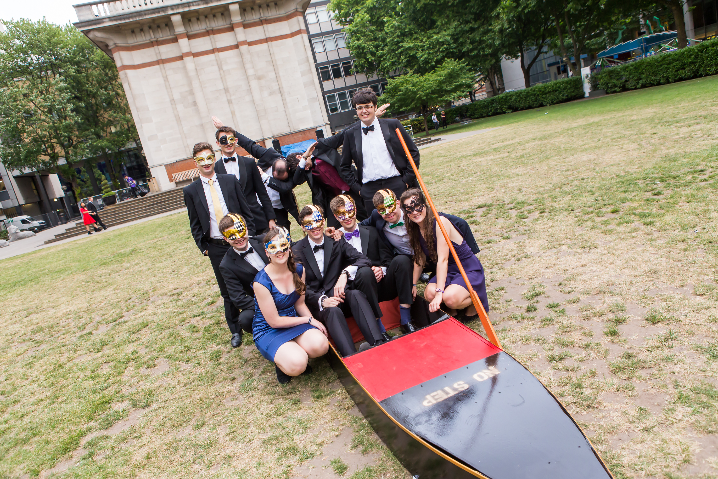 Group of friends posing with boat on Queen's Lawn.