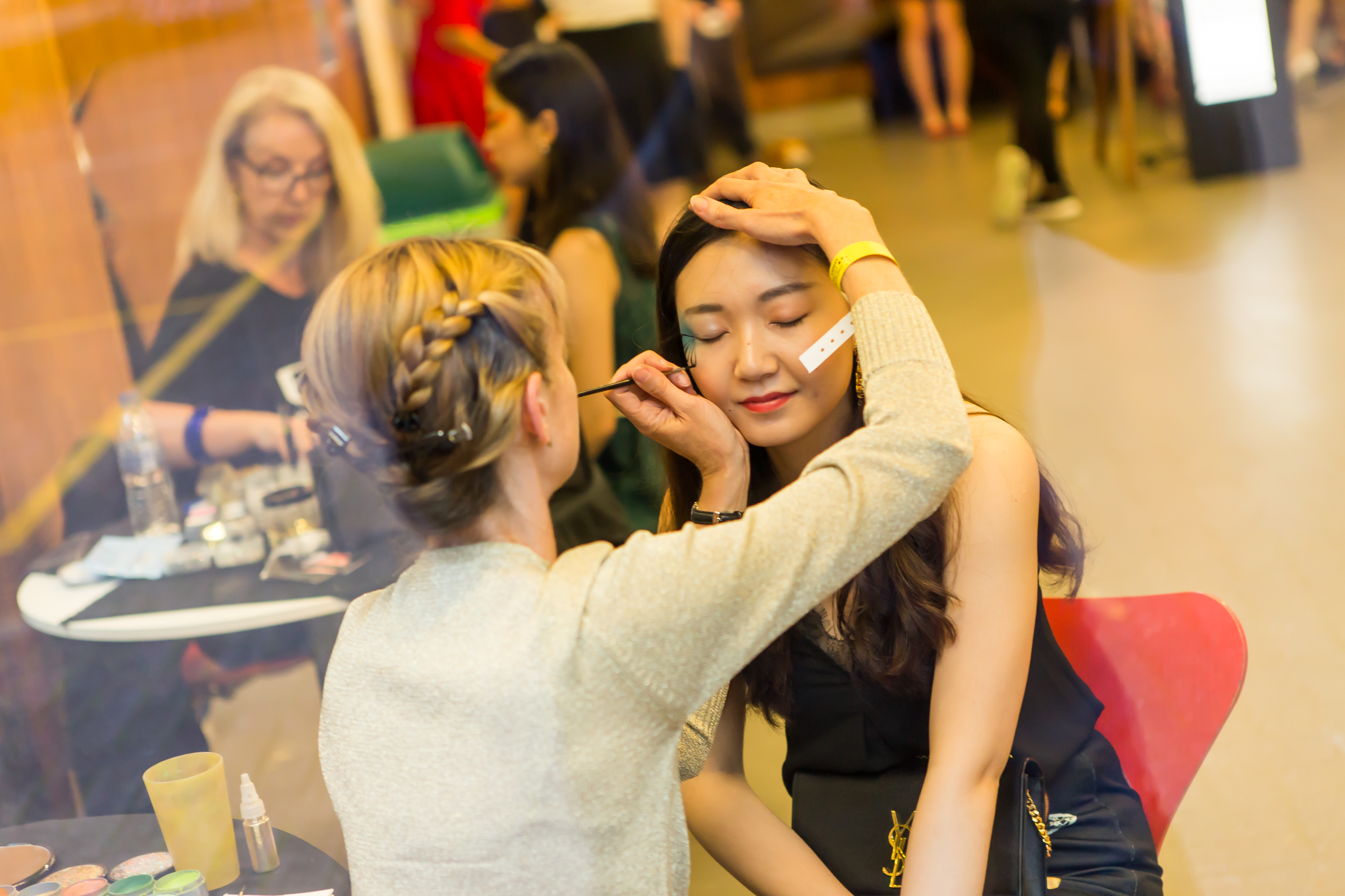 Make-up artist adding detail to student's face art.