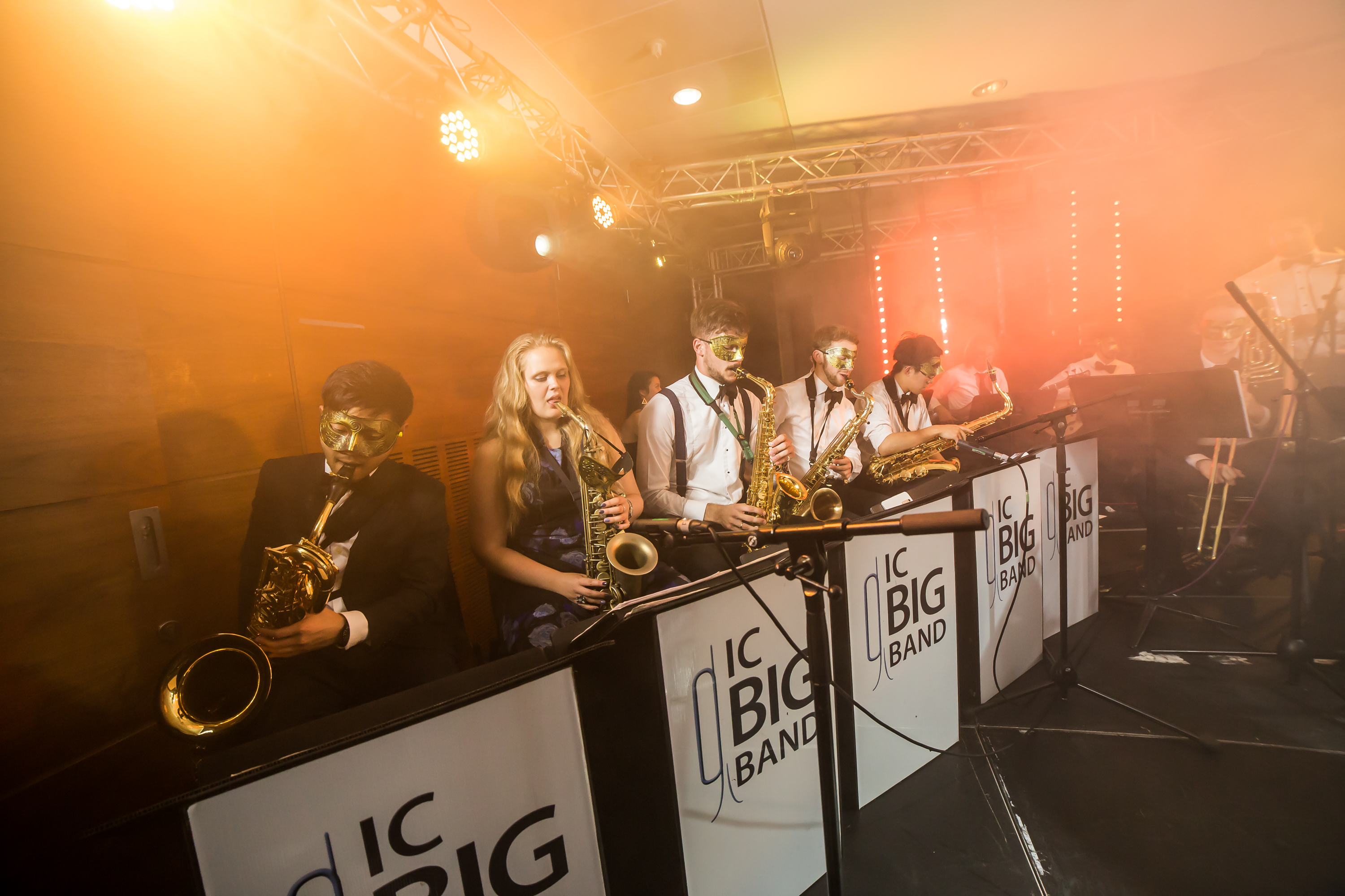 Big band saxophonists performing while wearing gold masks.