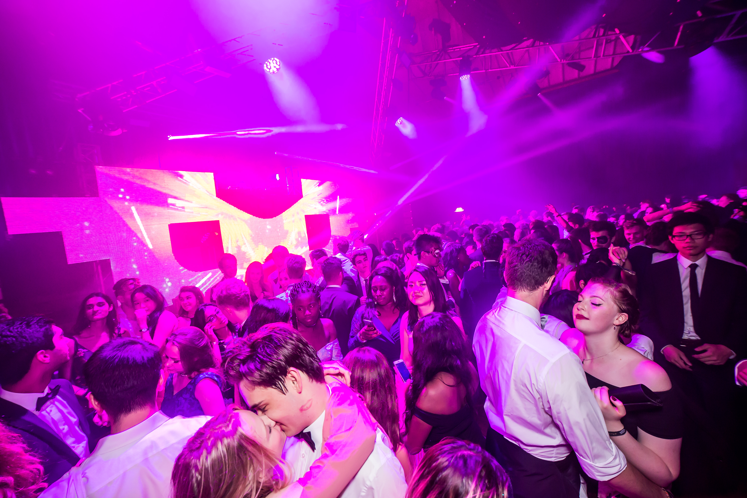 Great Hall dance floor with stage in the background and pink lighting.