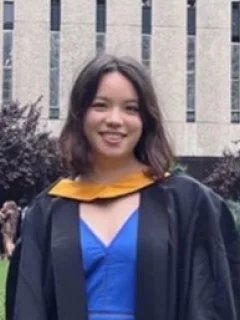Amandine in graduation robes on the Queens Lawn in front of the Abdus Salam Library